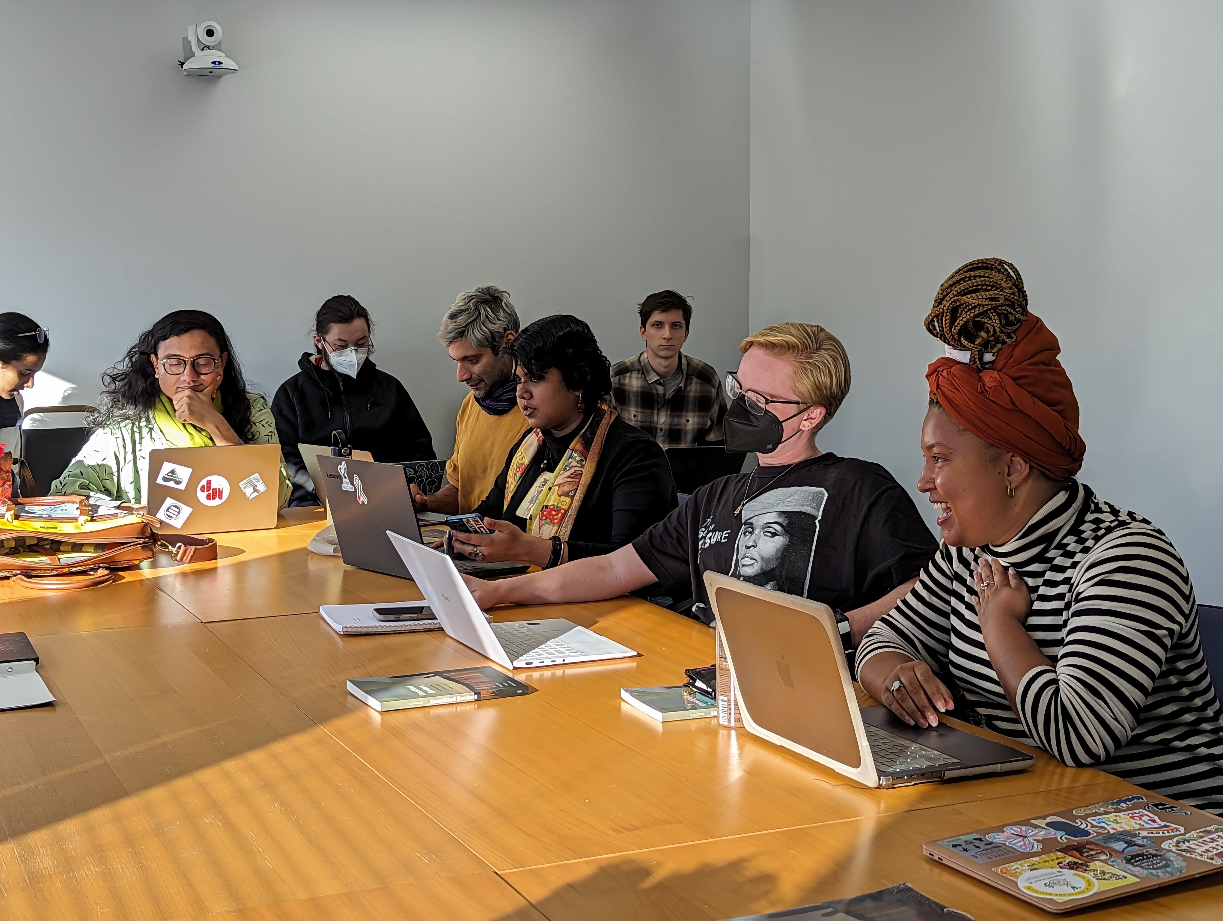 Diverse group of students and professors sit around a conference table in a sunny room